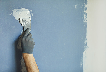 Expert drywall smoothing technique with precision tools and protective equipment